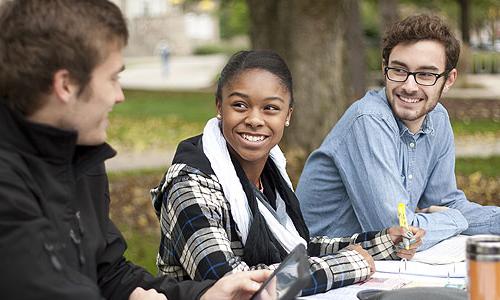 Three students doing homework on Main Lawn